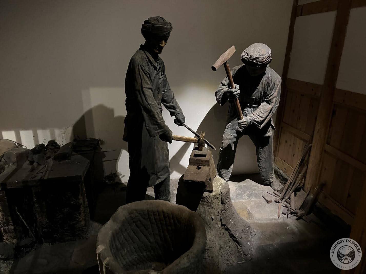 scene depicts two workers in a blacksmithing shop