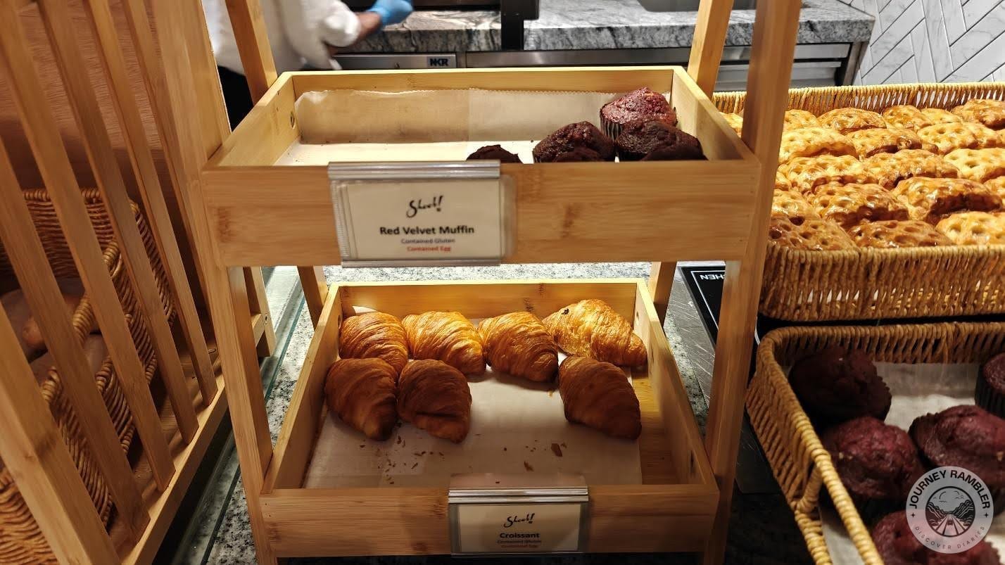 another shelf that contains croissants and red velvet muffins