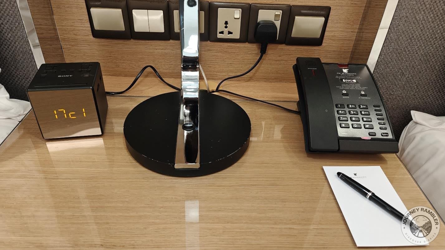 night table in between the two beds. It features a digital alarm clock as well as the room's telephone