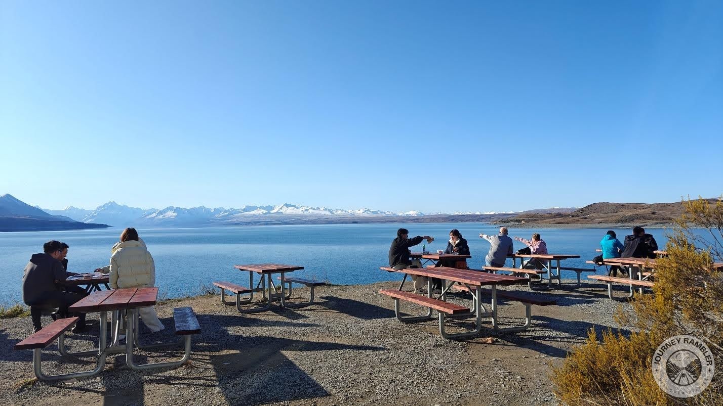 a lot of people were sitting on benches beside the lake