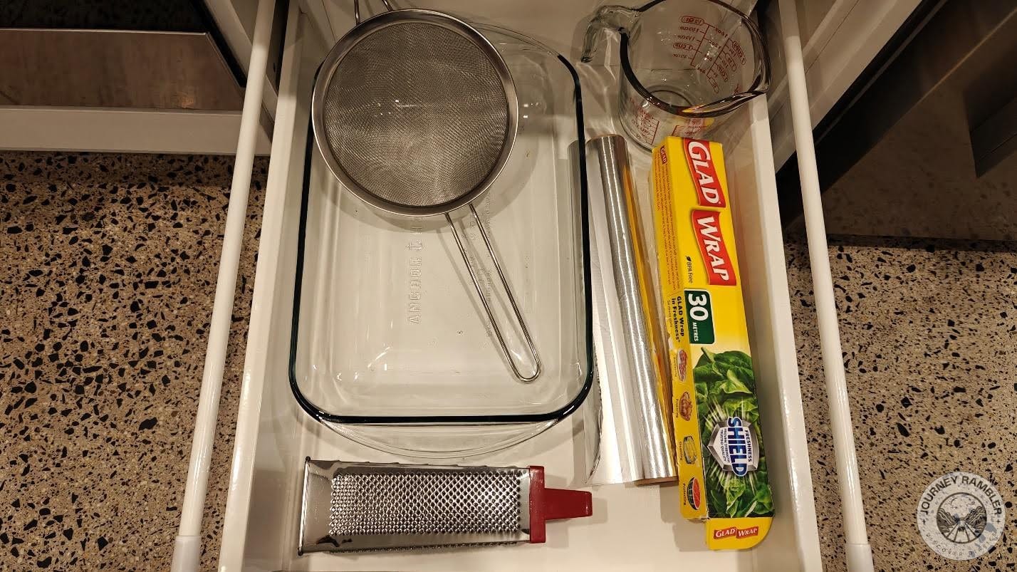 baking dish, a sieve, a measuring cup, a cheese grater and a roll of aluminum foil