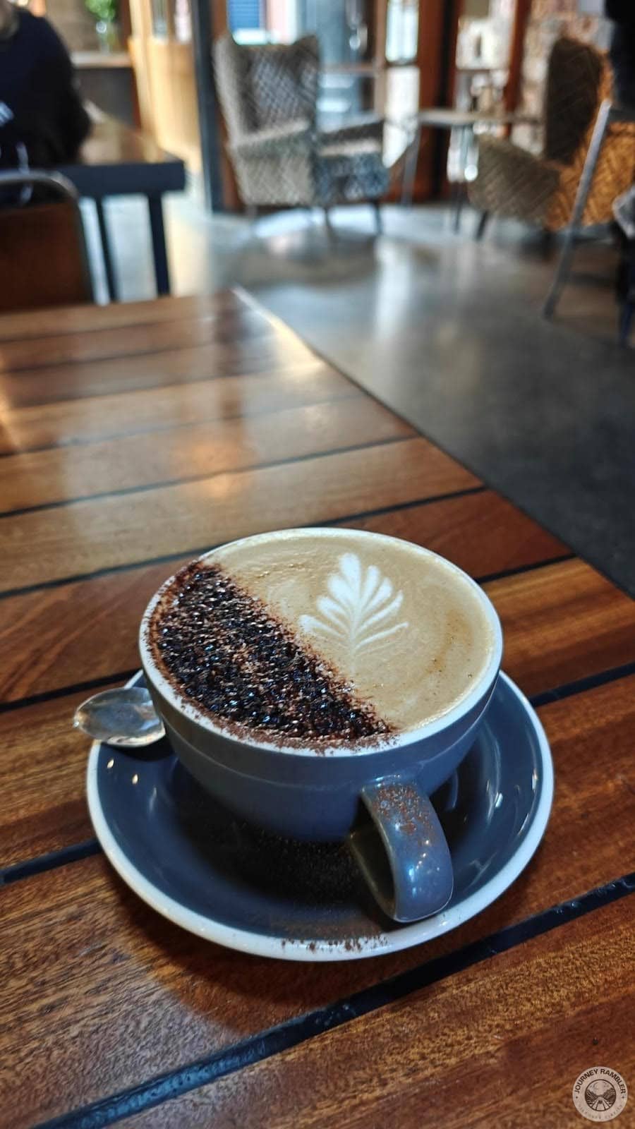 cappuccino decorated with a leaf pattern and dusted with some chocolate powder