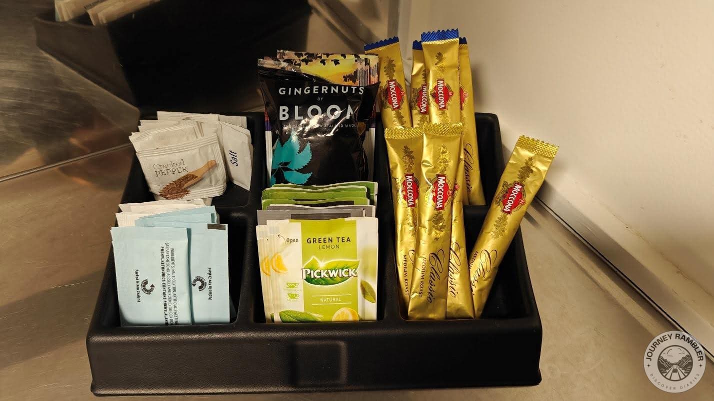 different flavored teas, sugar and coffee sachets, a packet of ginger biscuits and salt and pepper sachets