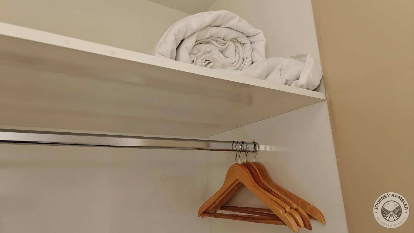 extra blanket on a shelf and racks were full of clothes hangers