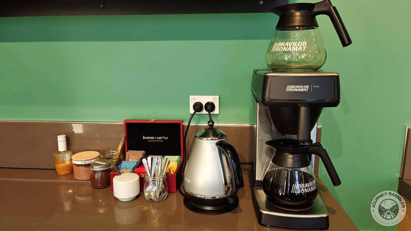 freshly brewed pot of coffee in the coffee maker and sachets of tea and sugar