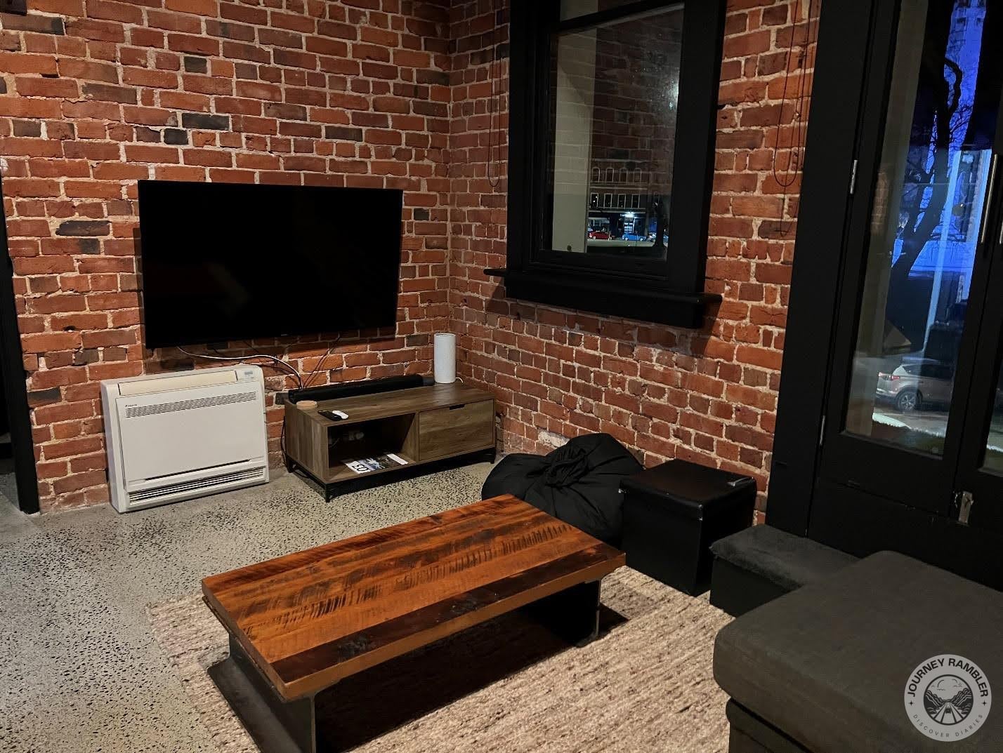 large TV was mounted on the wall opposite the sofa and a wooden coffee table