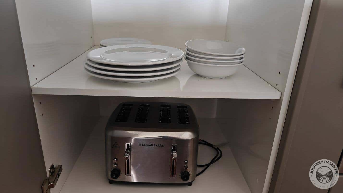 plates and bowls on the top shelf and a toaster on the bottom shelf