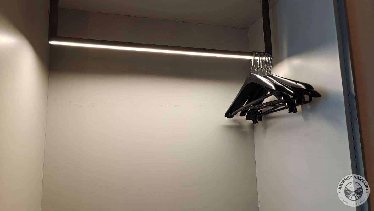 closet had some bare clothes hangers hanging from a rack