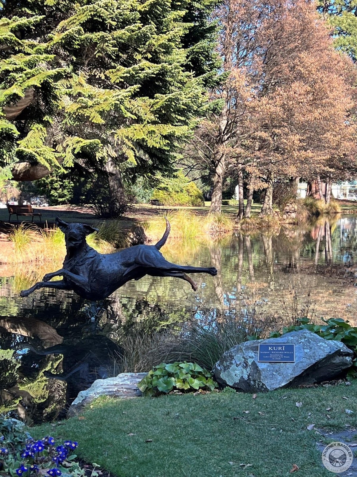 lifelike statue of a jumping dog right beside the pond