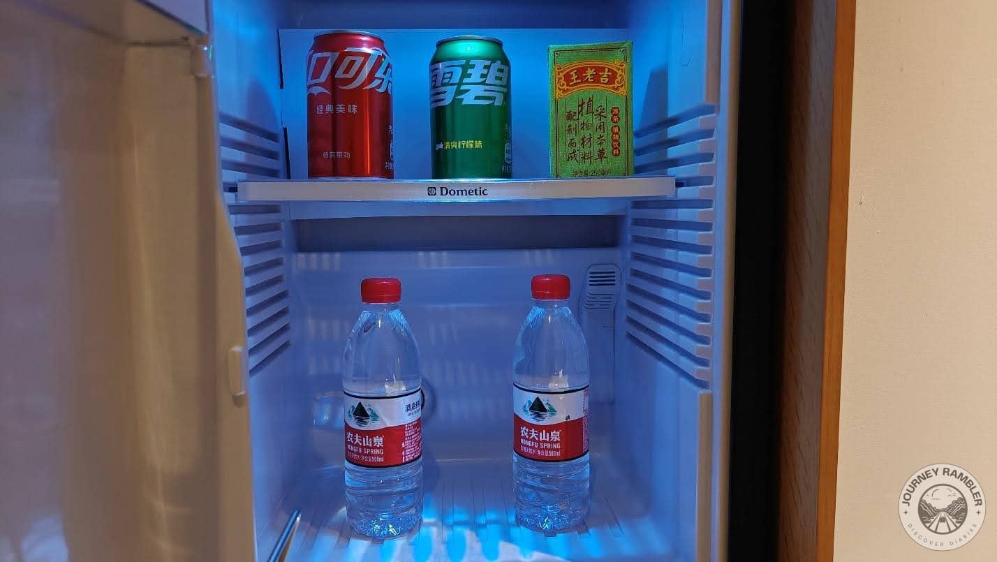 mini fridge with some cans of soda and water bottles inside