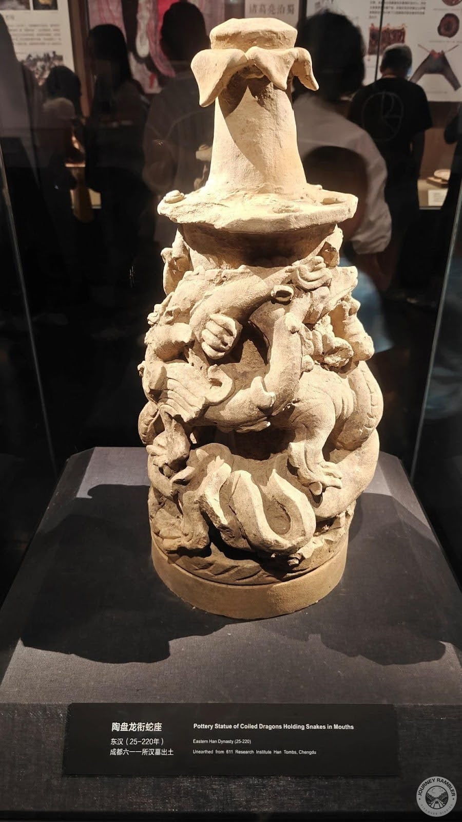 pottery statue of coiled dragons holding snakes in mouths