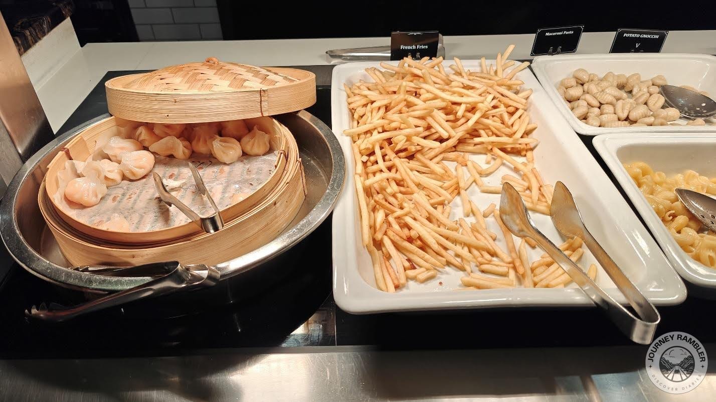 steamed dumplings in a large bamboo steamer right next to a huge tray of crispy French fries