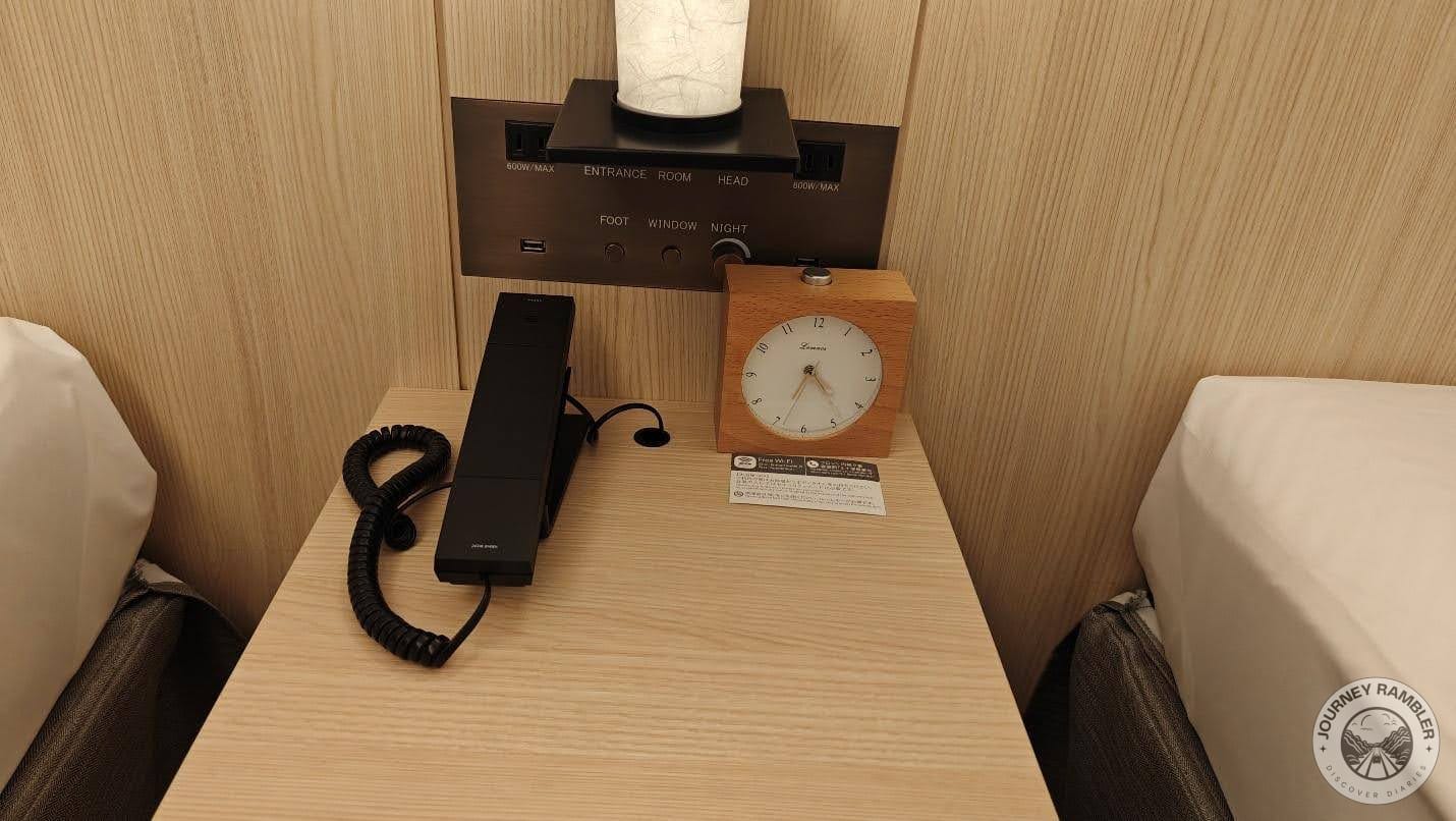 cool alarm clock and a telephone and intercom system on the nightstand