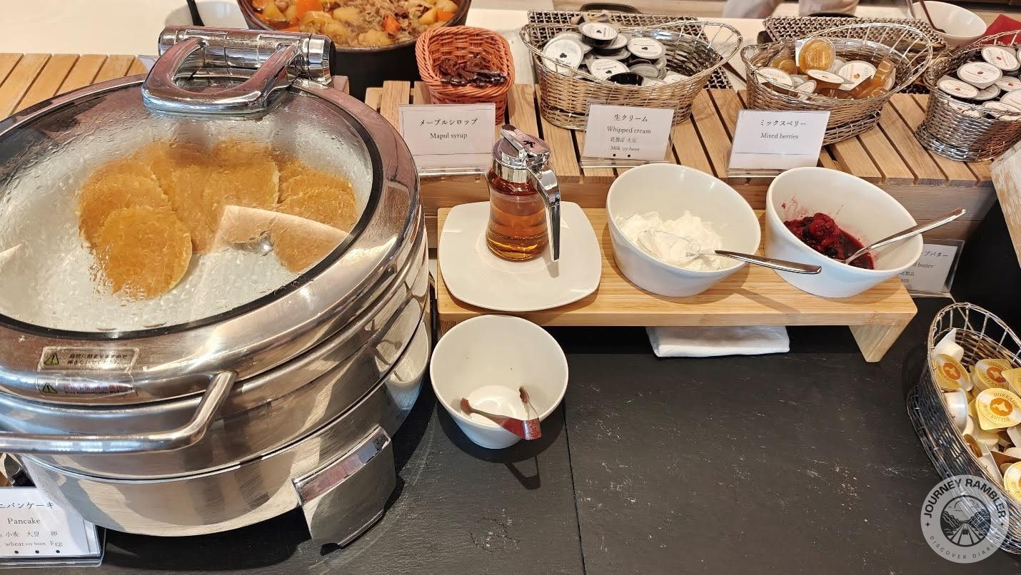 pancakes with maple syrup, whipped cream and different kinds of jam