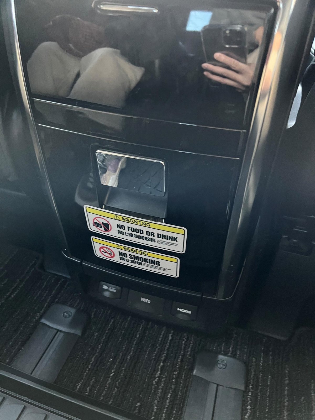 Car console with no food, drink, or smoking signs, dark interior.