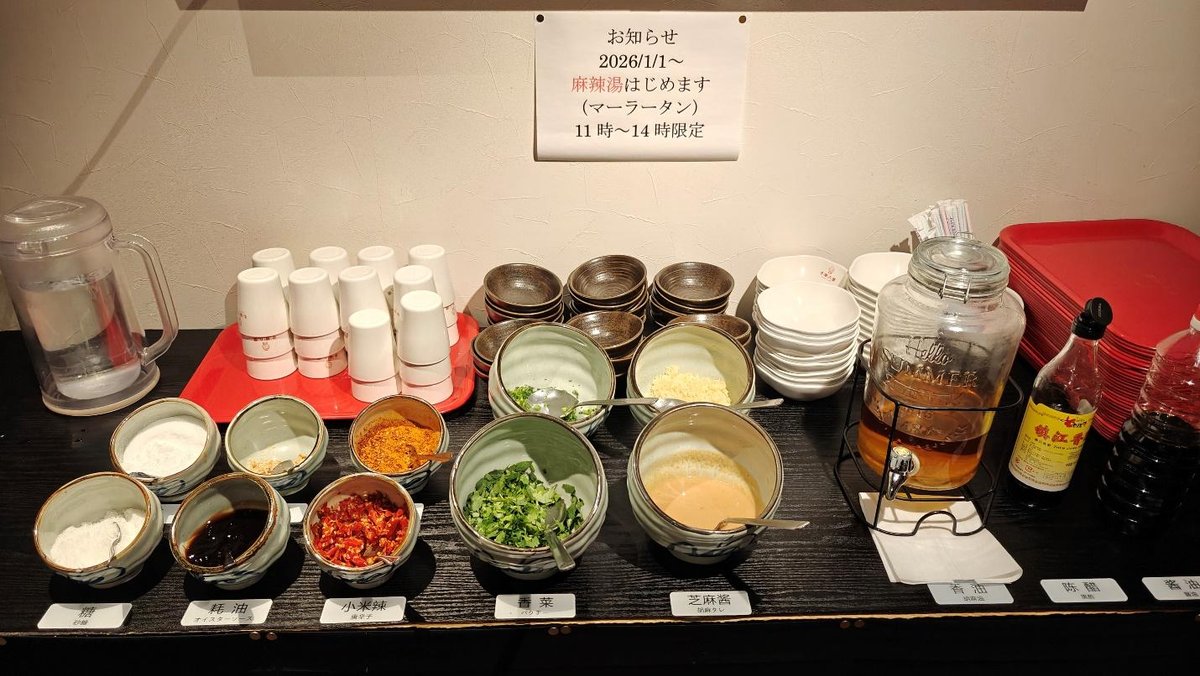Condiments and spices on a counter, with cups, jars, and trays.