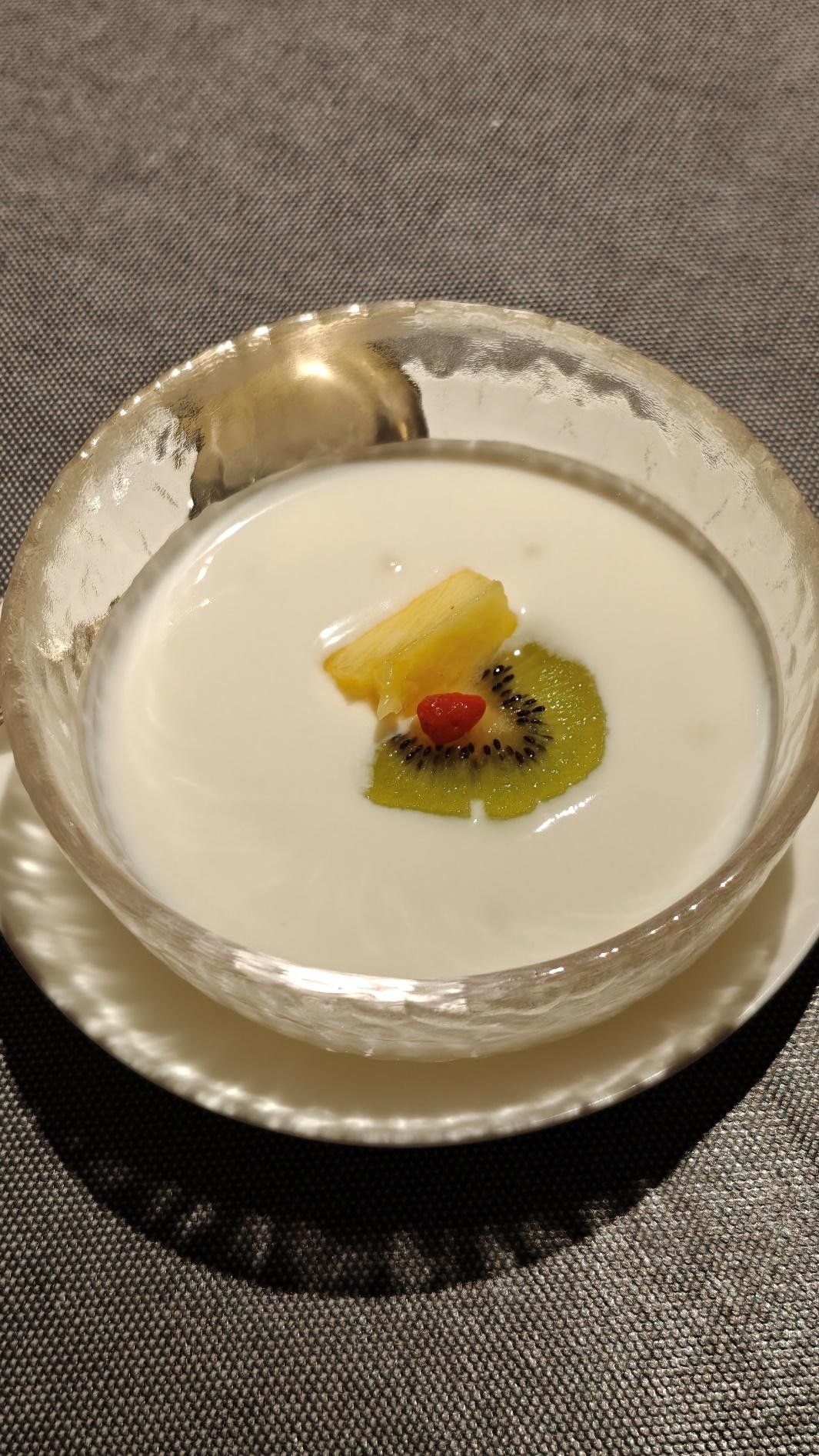 Creamy dessert with kiwi, pineapple, and berry in a glass bowl.