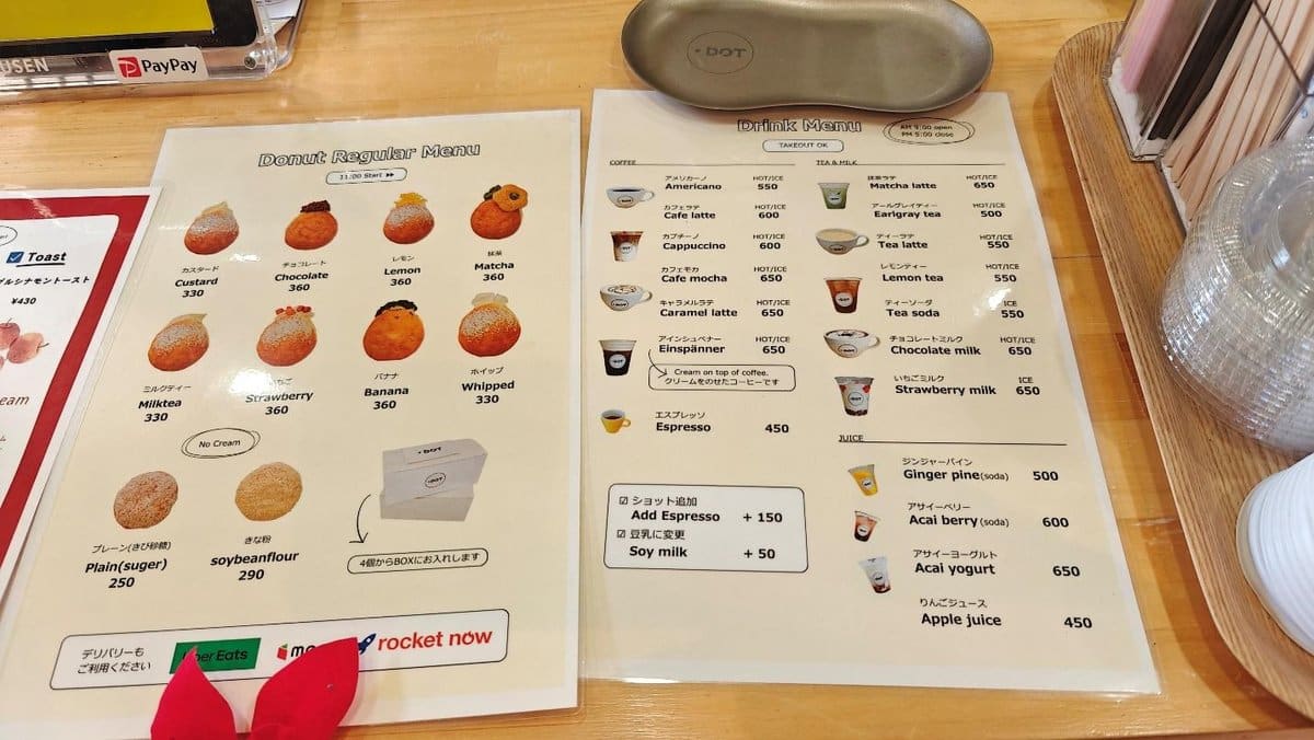 Donut and drink menu on a wooden table with prices listed.