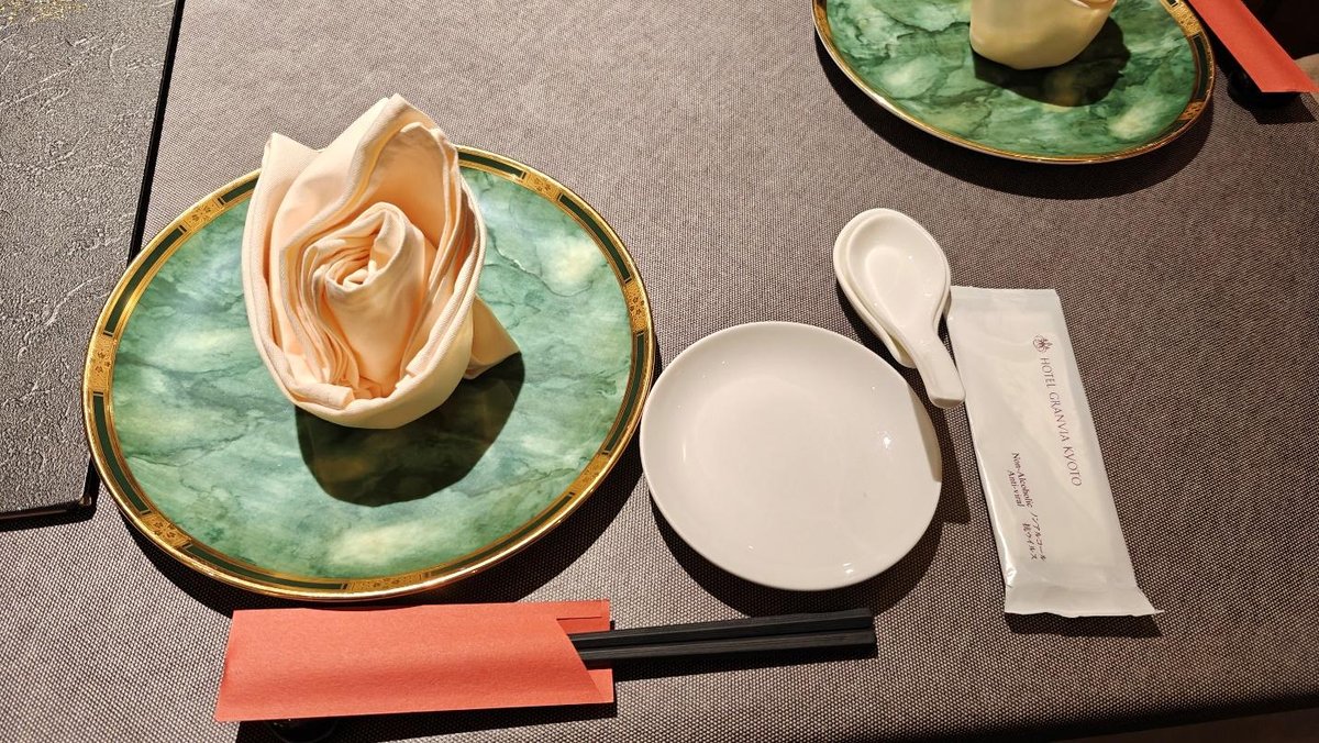 Elegant table setting with folded napkin, green plate, and chopsticks.
