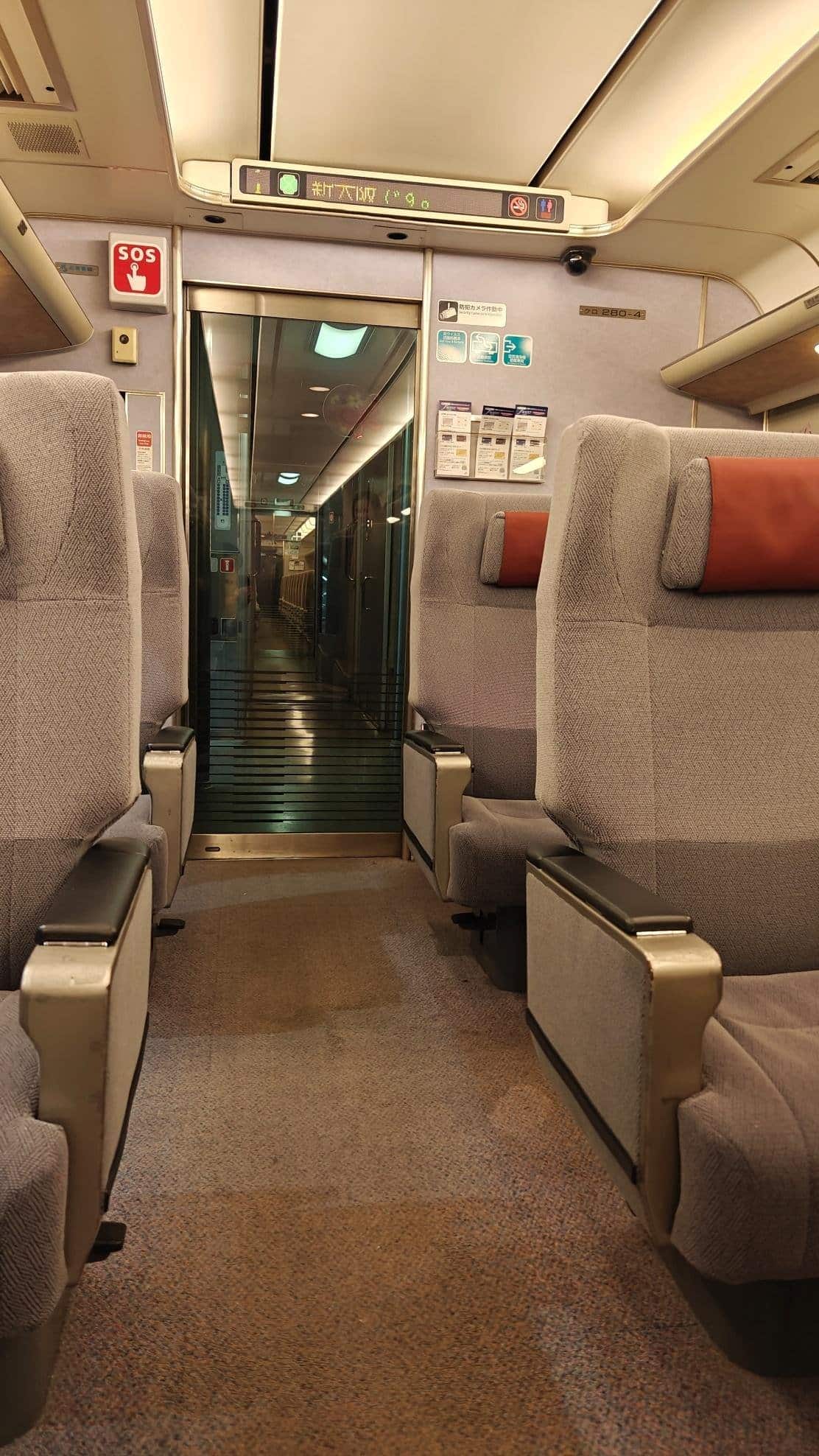 Empty train aisle with gray seats and beige interior. Cozy and orderly atmosphere.