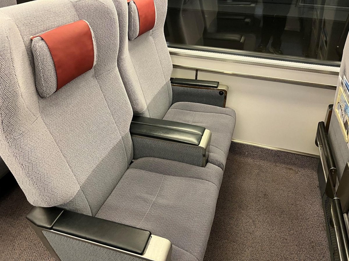 Gray train seats with red headrests and black armrests.