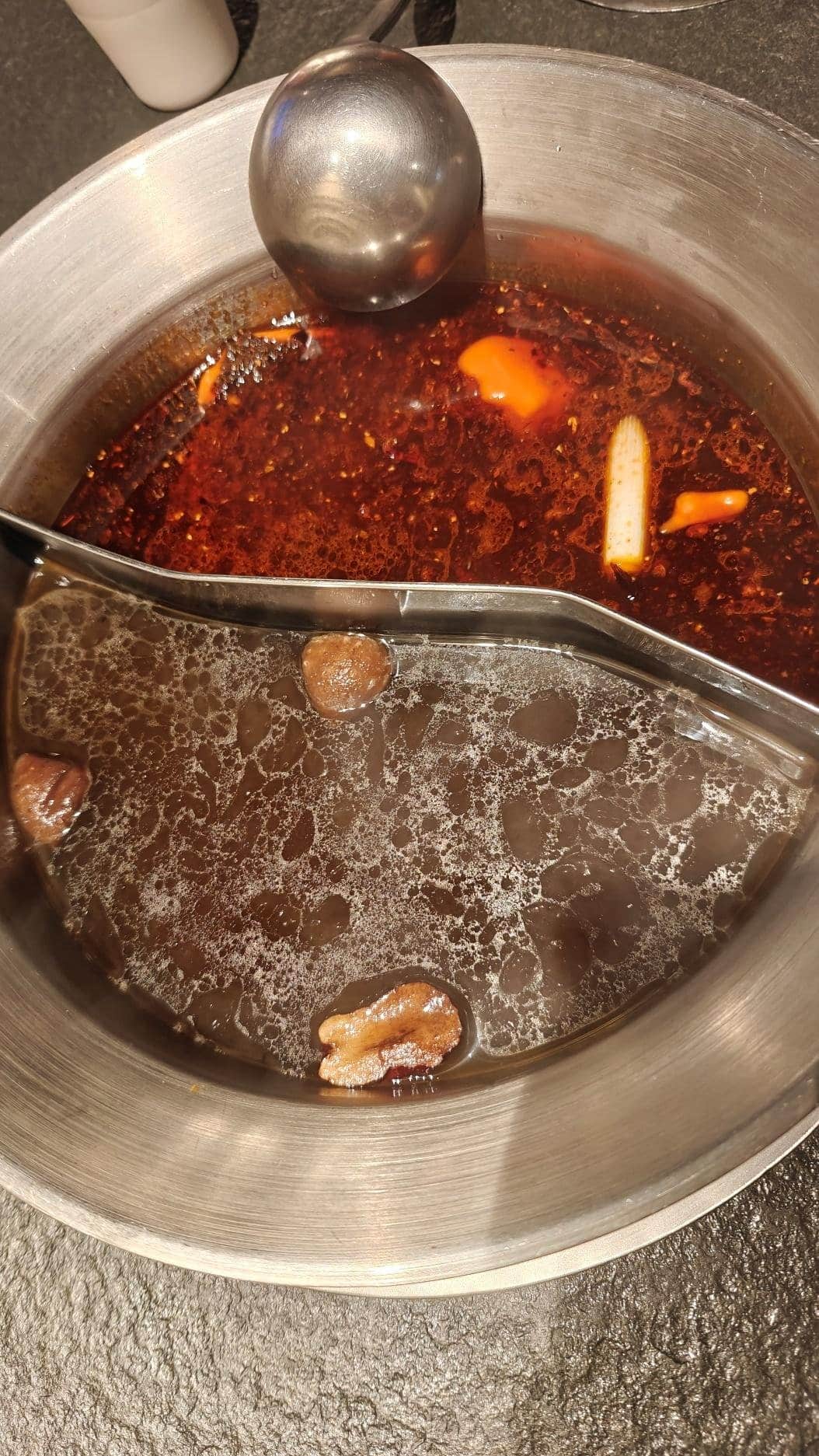 Hot pot with spicy red broth and savory clear broth, separated by divider.
