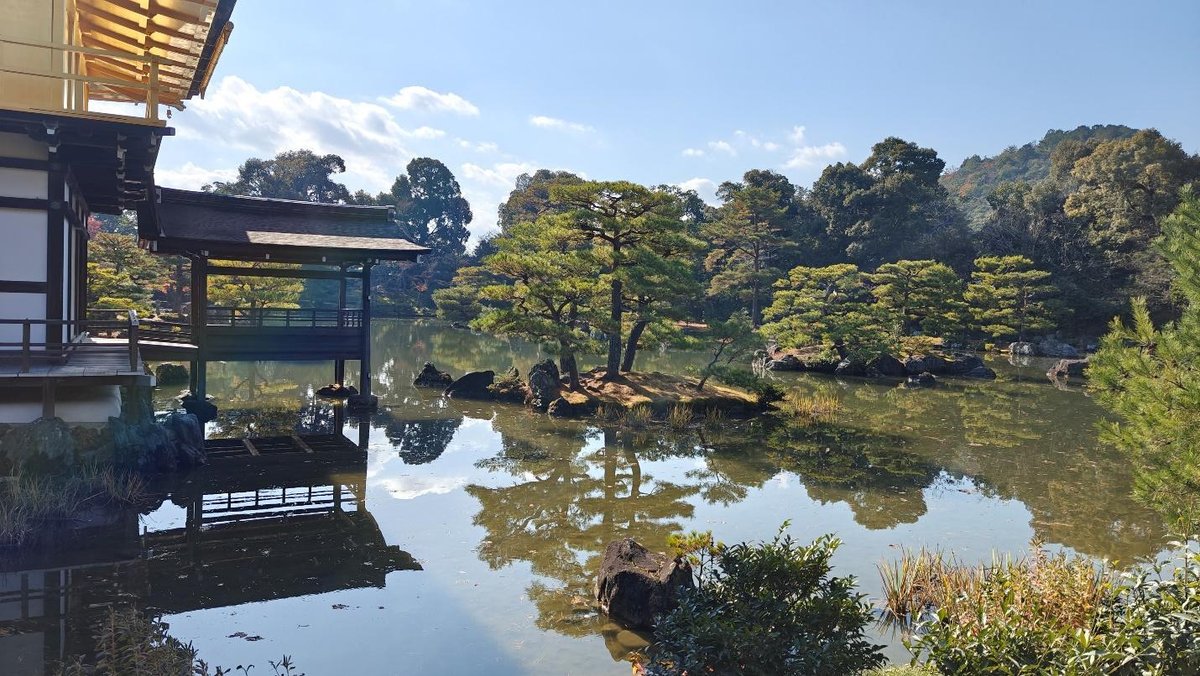 Japanese garden with pond, pavilion, reflection, and lush greenery.