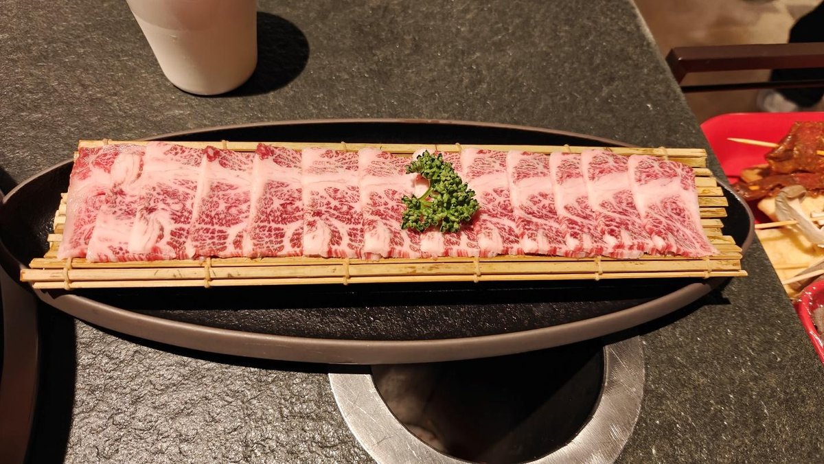 Marbled beef slices on bamboo tray with parsley garnish.
