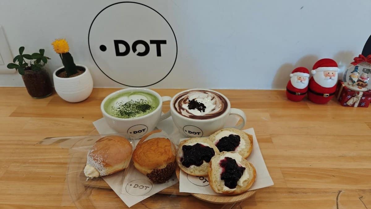 Matcha latte, hot chocolate, pastries on a wooden table, festive decor.