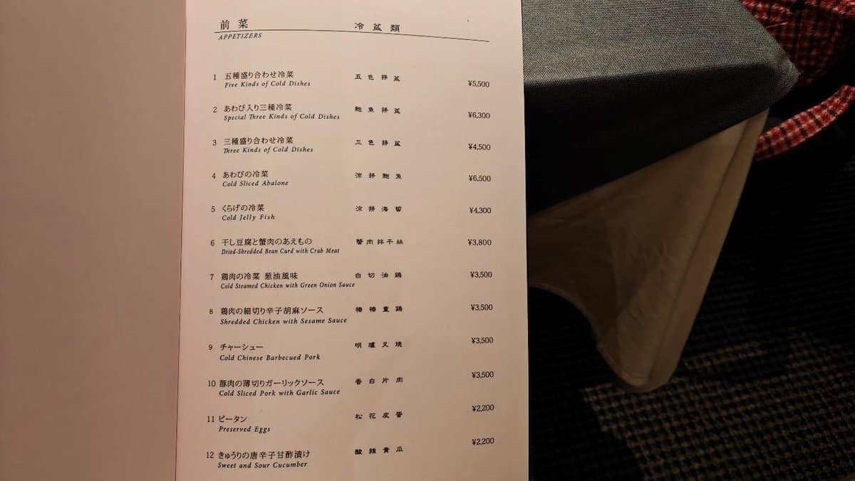 Menu listing various cold appetizers with prices in a dim setting.