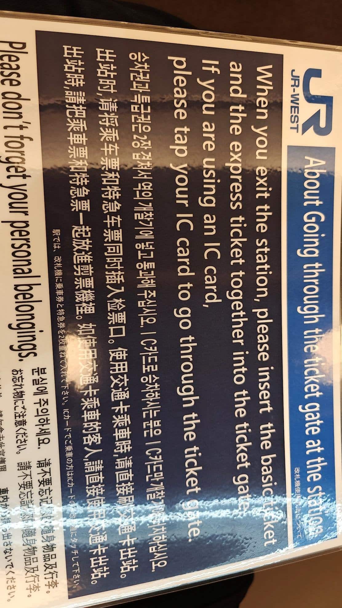 Multilingual station ticket gate instructions on a blue sign.