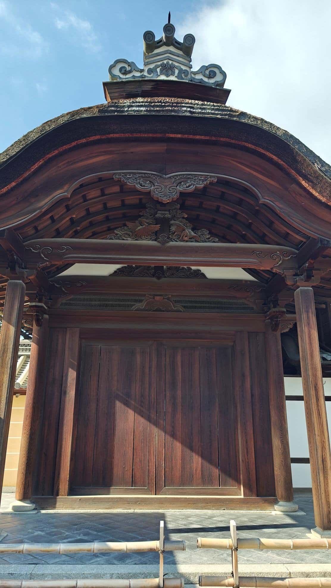 Ornate wooden temple entrance with intricate carvings under blue sky.