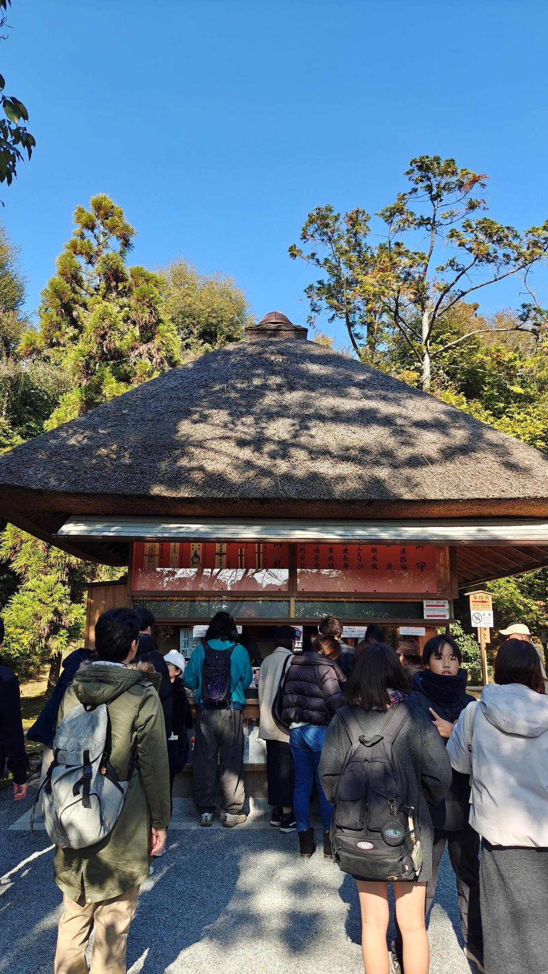 People at a thatched-roof kiosk under a clear blue sky.