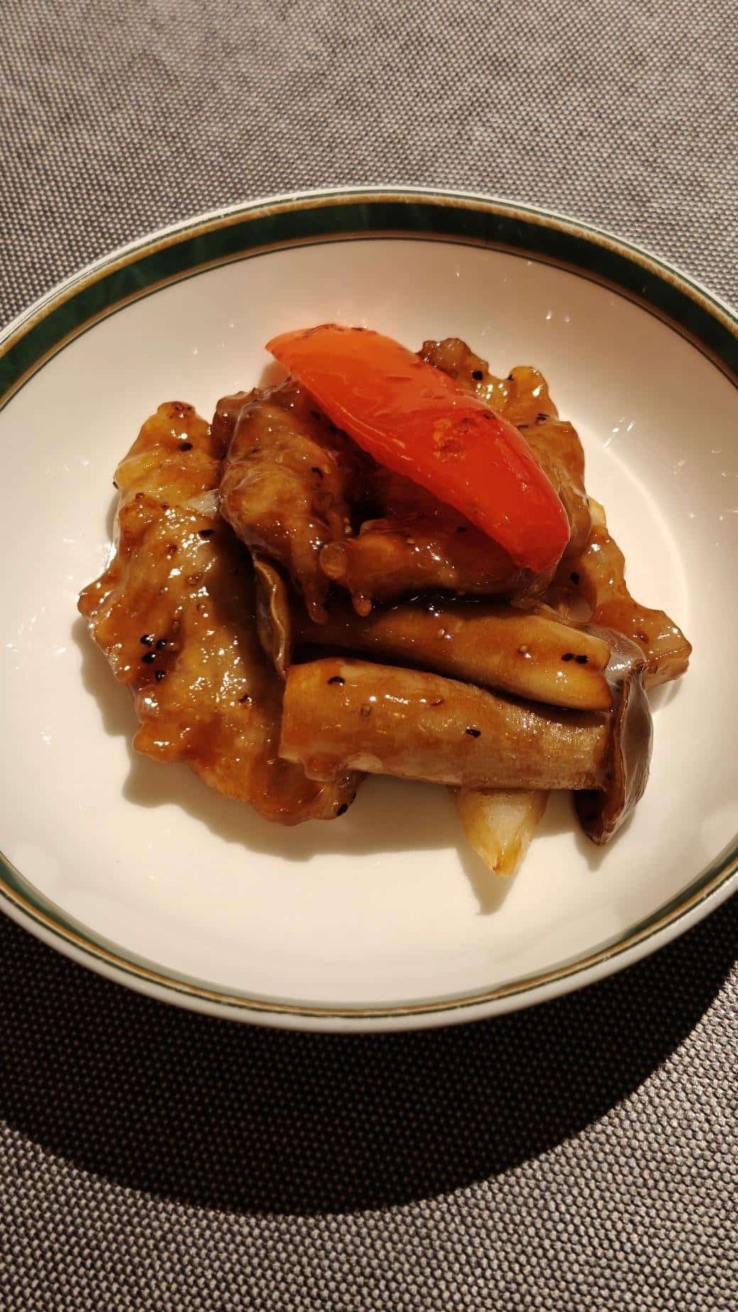 Plate with glazed mushrooms and red pepper on a white dish.