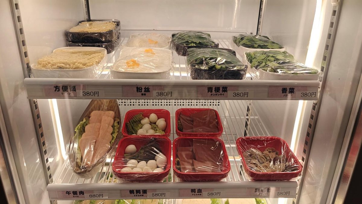 Refrigerator shelves with packaged noodles and vegetables.