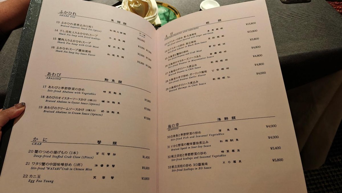 Restaurant menu with dishes like shark fin and abalone. Elegant setting.