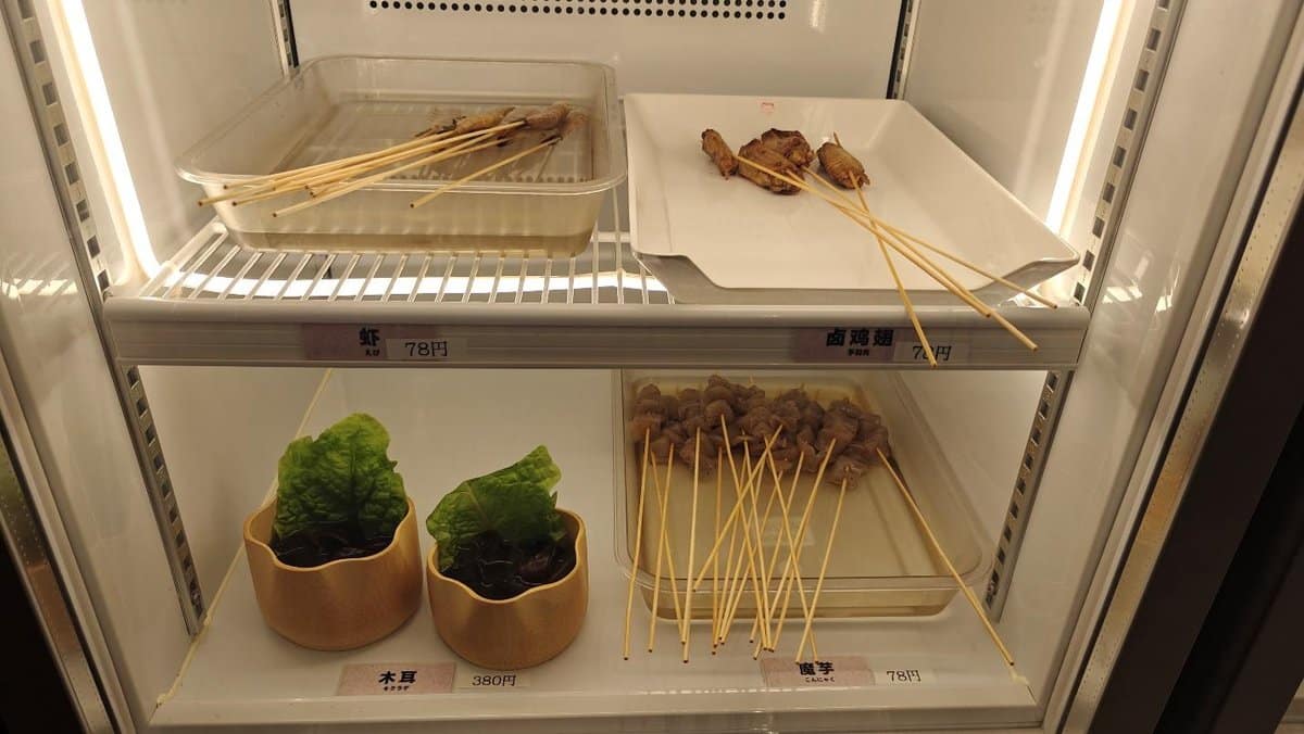 Skewered meats and lettuce cups displayed in a refrigerated case.