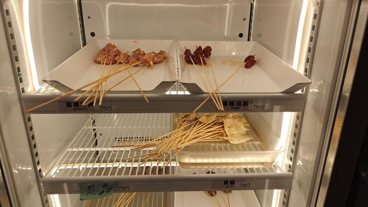 Skewered meats and tofu displayed in a refrigerated case.