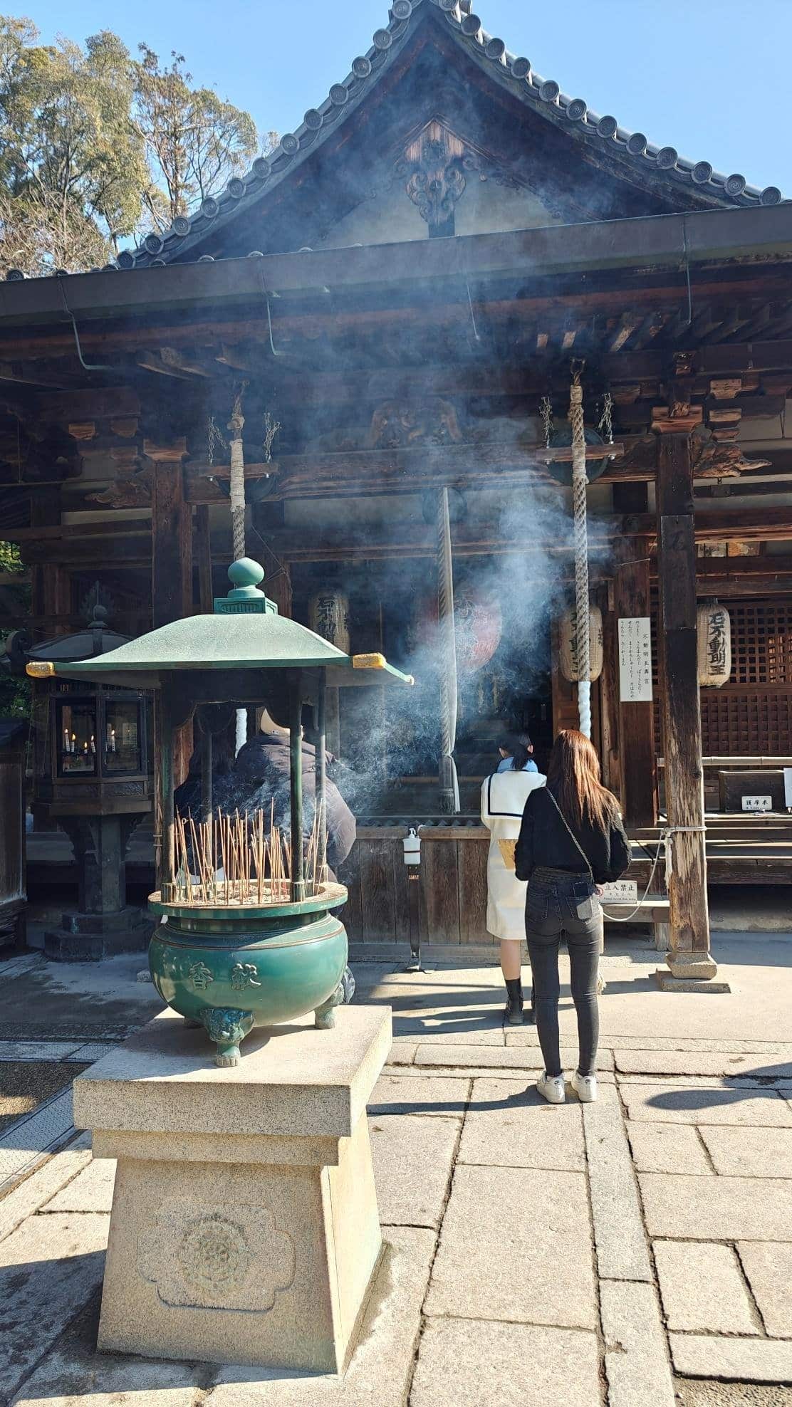 Temple entrance with incense burner and smoke, blue sky background.