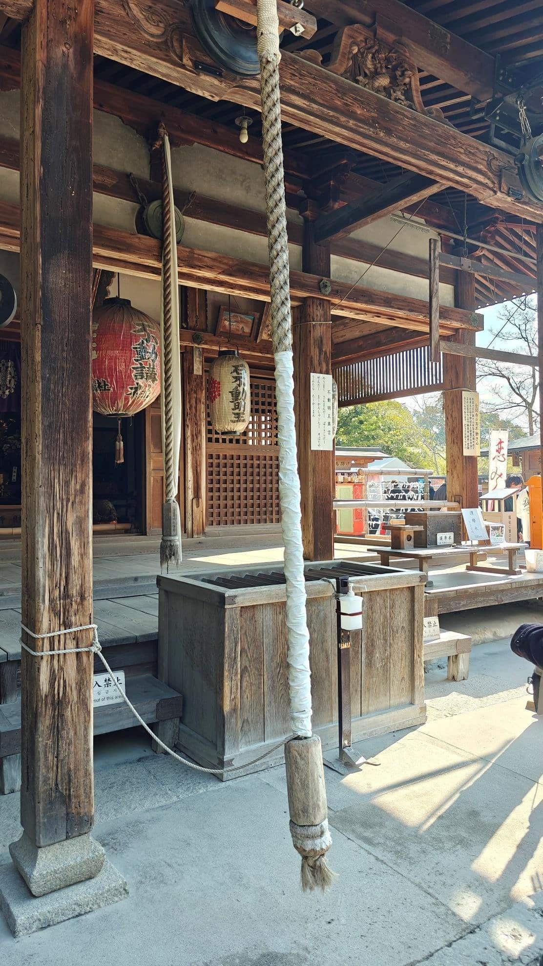 Traditional Japanese shrine with wooden architecture and large rope bell.