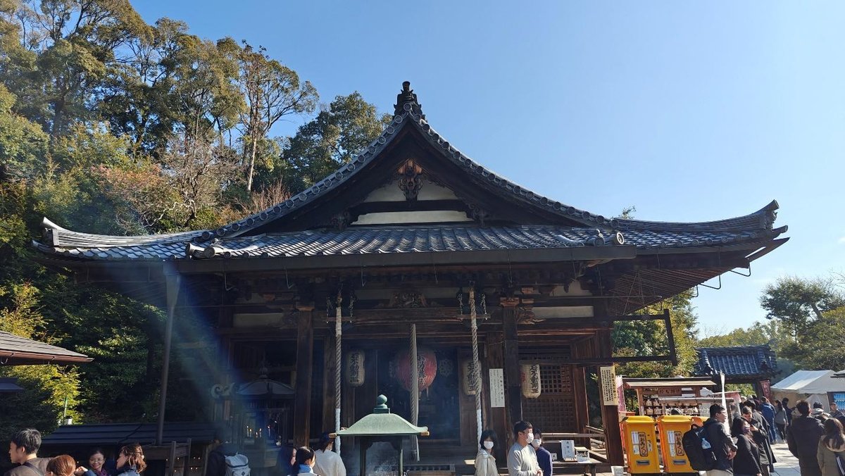 Traditional Japanese temple with ornate roof, surrounded by trees and visitors.