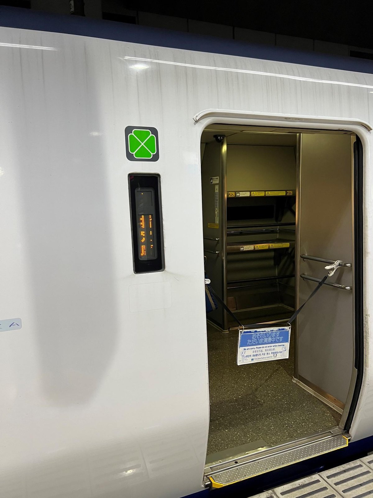 Train door slightly open at station, safety barrier visible inside.