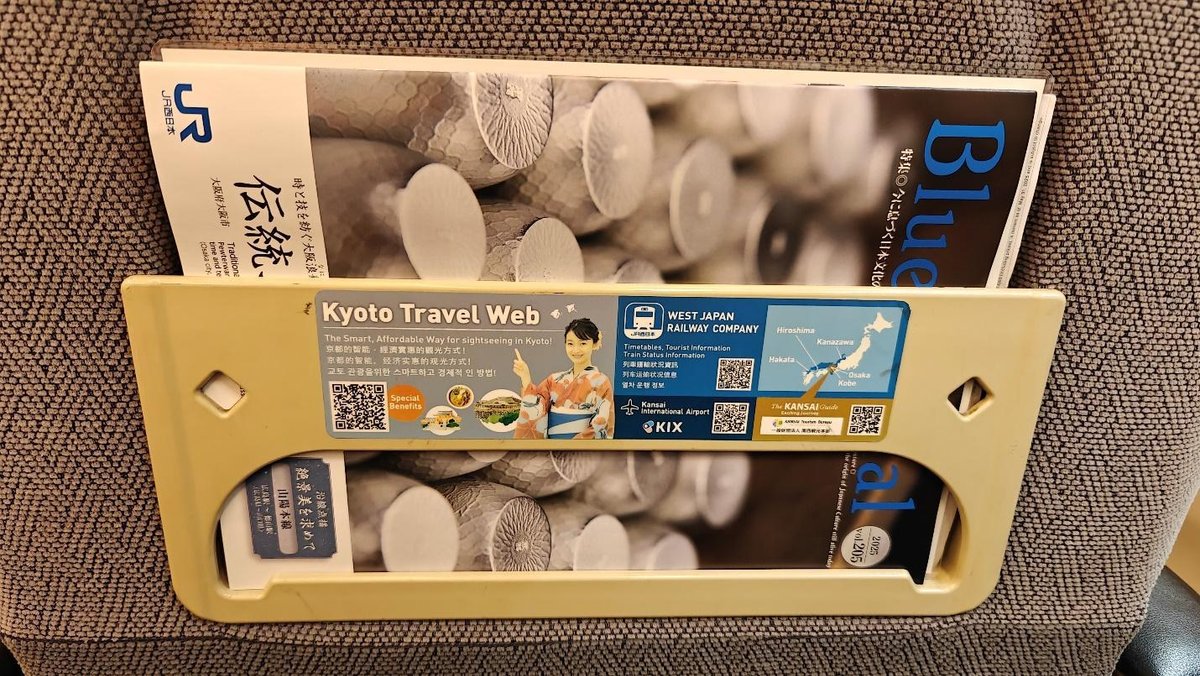 Travel brochures in a train seat pocket, promoting Kyoto and Kansai travel.
