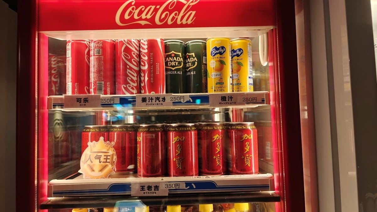 Vending machine with Coca-Cola, ginger ale, and orange juice cans.