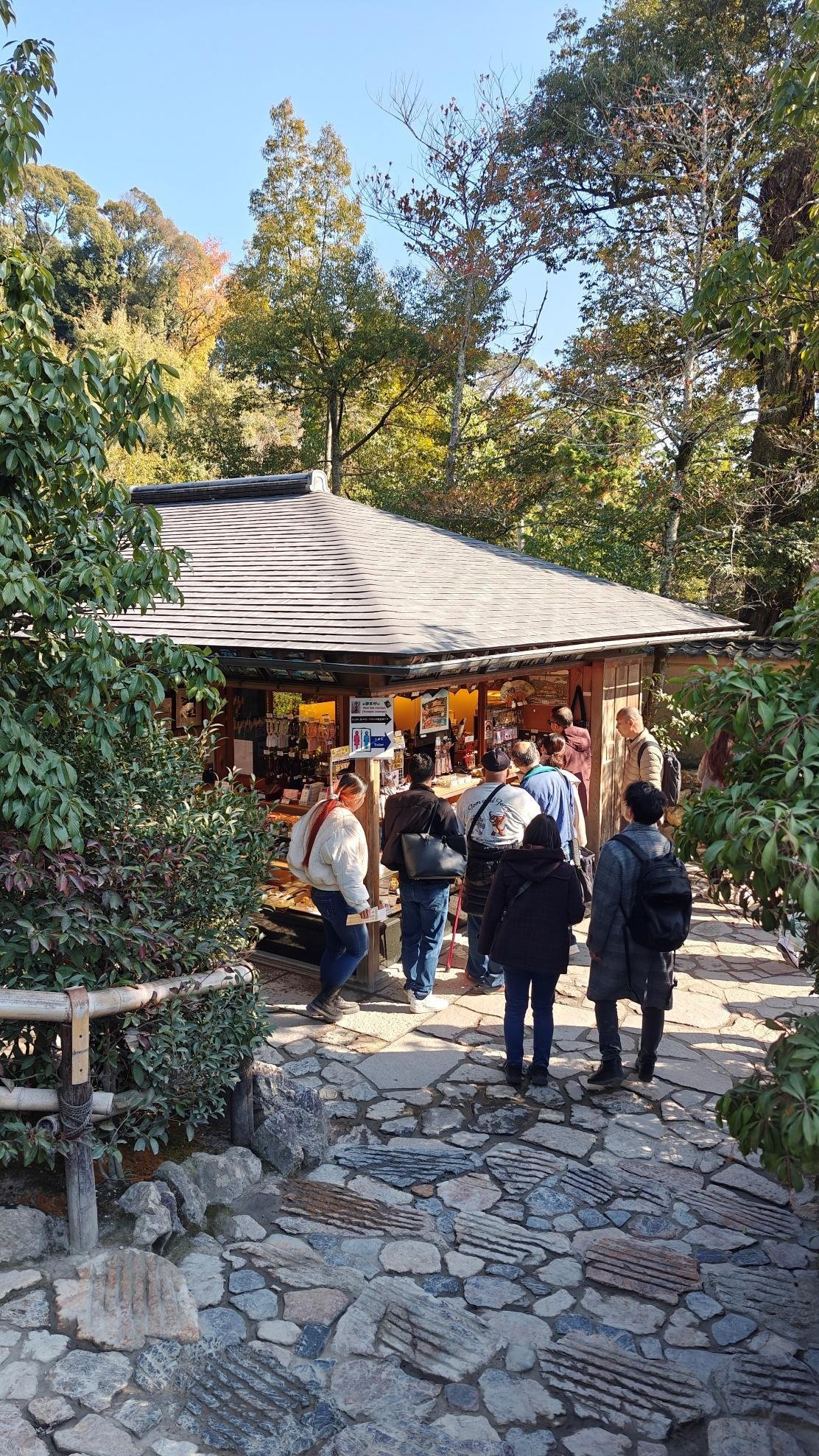 Visitors at a rustic wooden kiosk surrounded by lush greenery and trees.