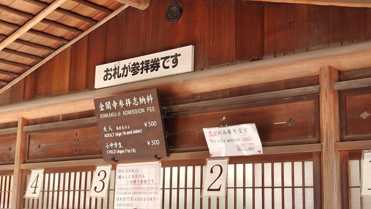Wooden ticket booth, signs with admission fees, and cash-only notice.