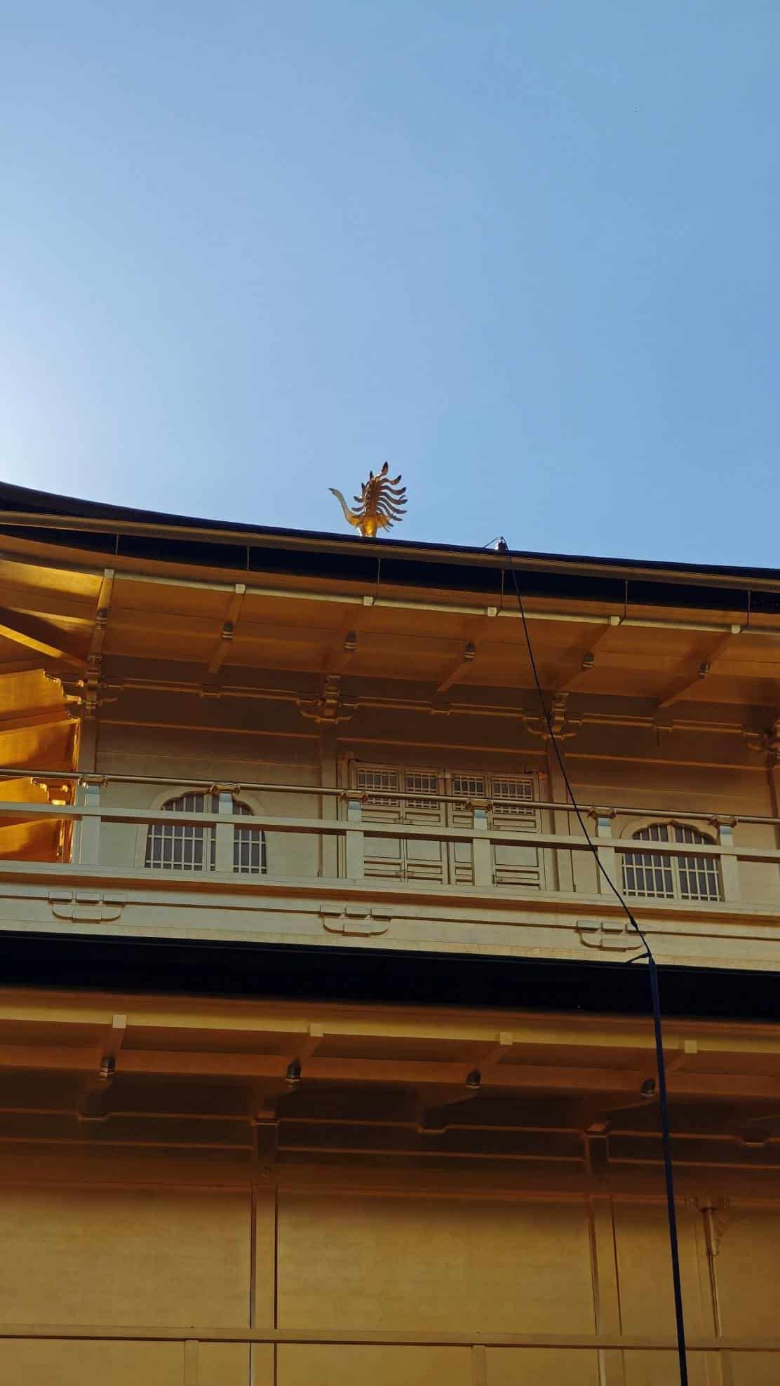 Yellow building facade with ornate rooftop decoration under blue sky.