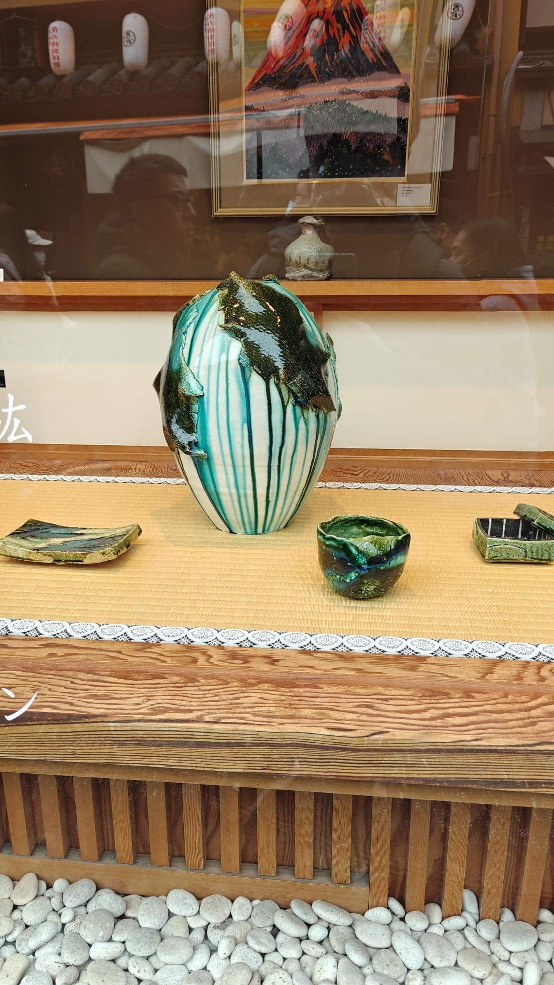 Ceramic art display with vase and bowls on wooden shelf