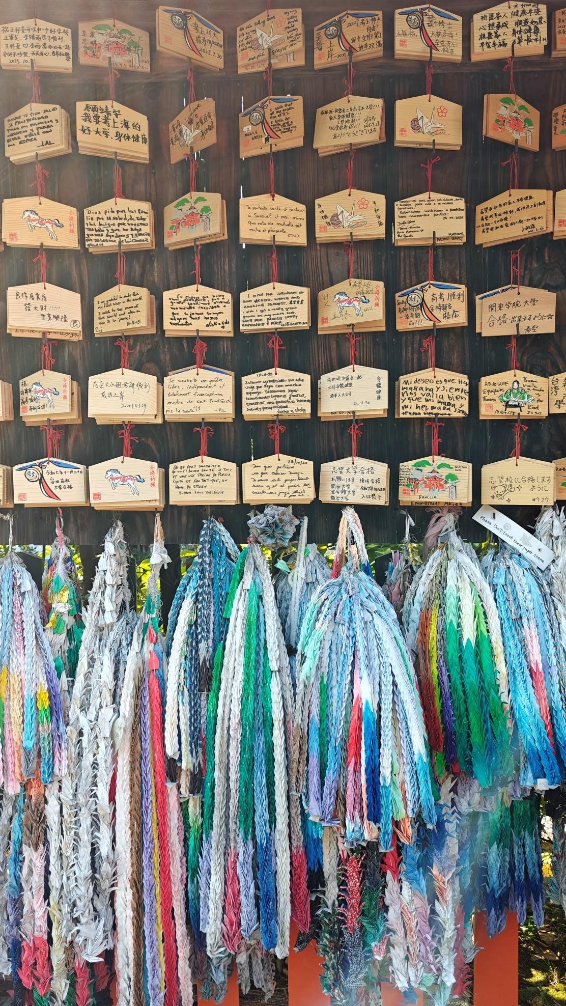 Colorful origami cranes and wooden prayer plaques display