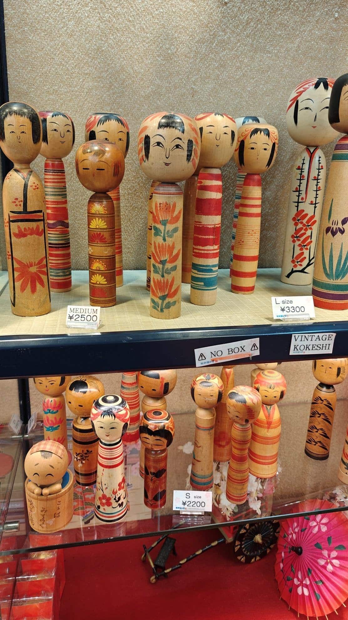 Colorful vintage Kokeshi dolls on display shelves